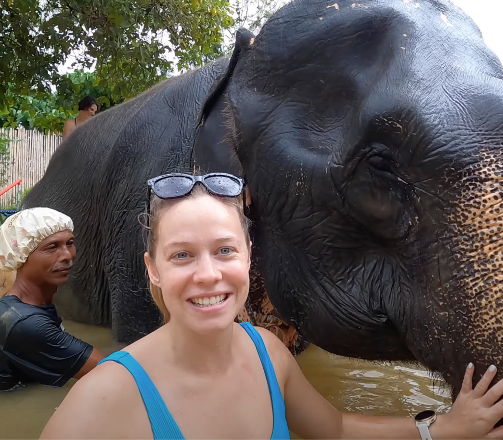 Personne se baignant avec un éléphant dans un sanctuaire en Thaïlande, illustrant une interaction respectueuse et naturelle avec l'animal.